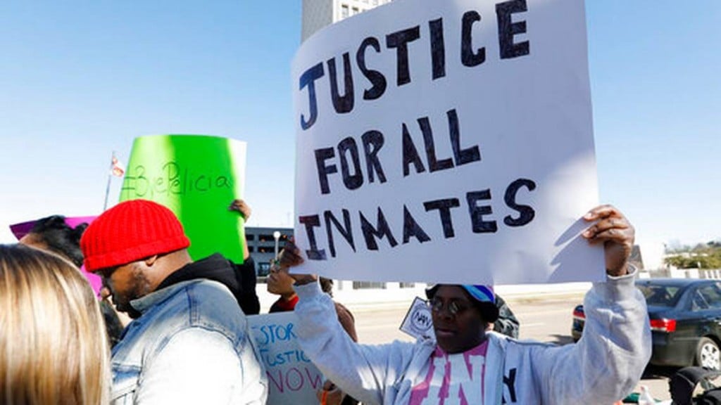 Prisoner advocates hold signs supporting inmate rights at a protest outside the Capitol in Jackson