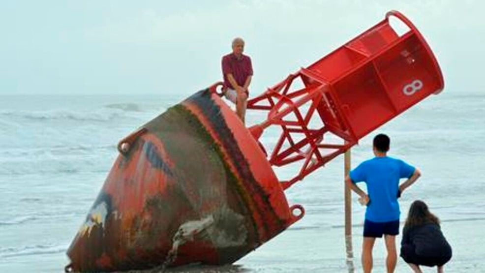 REMOVES REFERENCE TO MOVING THE BUOY ON MONDAY - Beachgoers inspect a navigational marker that washed up on the beach last week in New Smyrna Beach